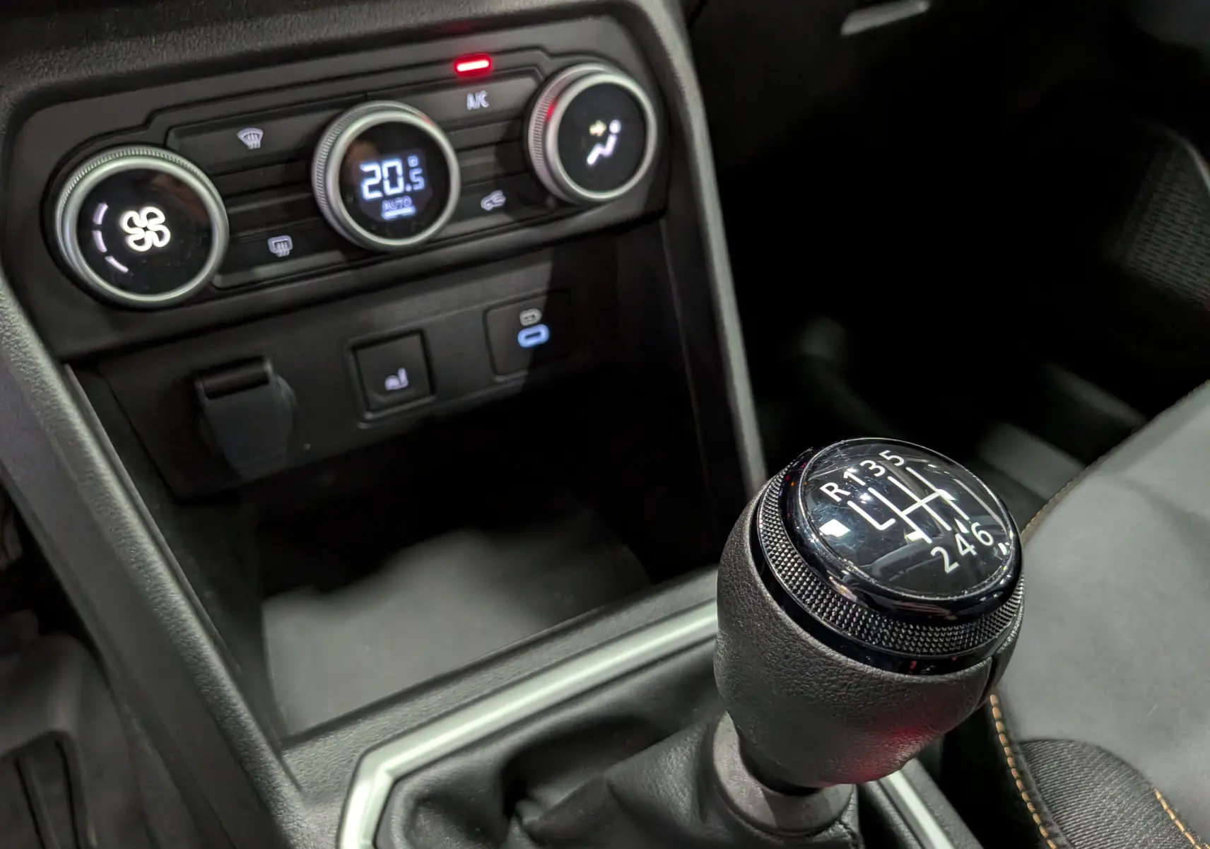 Gros plan sur la commande de la boîte manuelle et la console de climatisation du Dacia Sandero Stepway TCe 110 Gris Schiste.