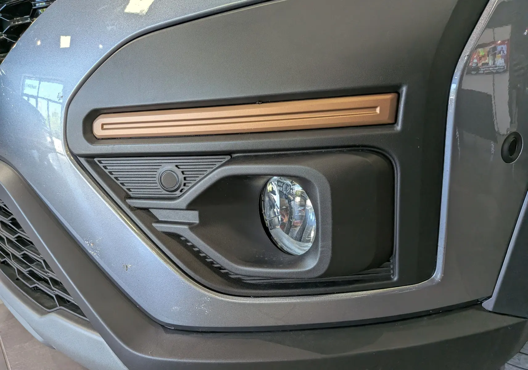 Gros plan sur le feu antibrouillard avant droit du Dacia Sandero Stepway 2025 en gris schiste avec insert décoratif bronze.
