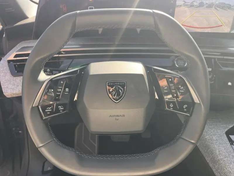 Vue rapprochée du volant cuir multifonction noir avec logo Peugeot au centre du 3008 gris Artense.