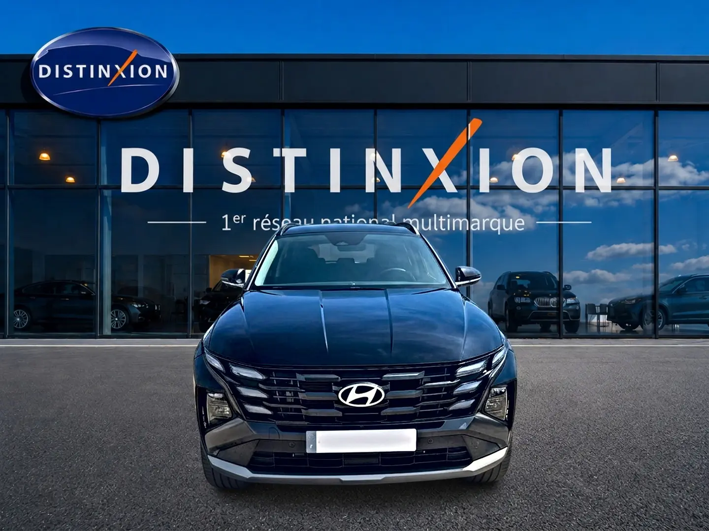 Vue de face d'un Hyundai Tucson noir 2026 avec calandre large et phares LED, devant une vitrine Distinxion.