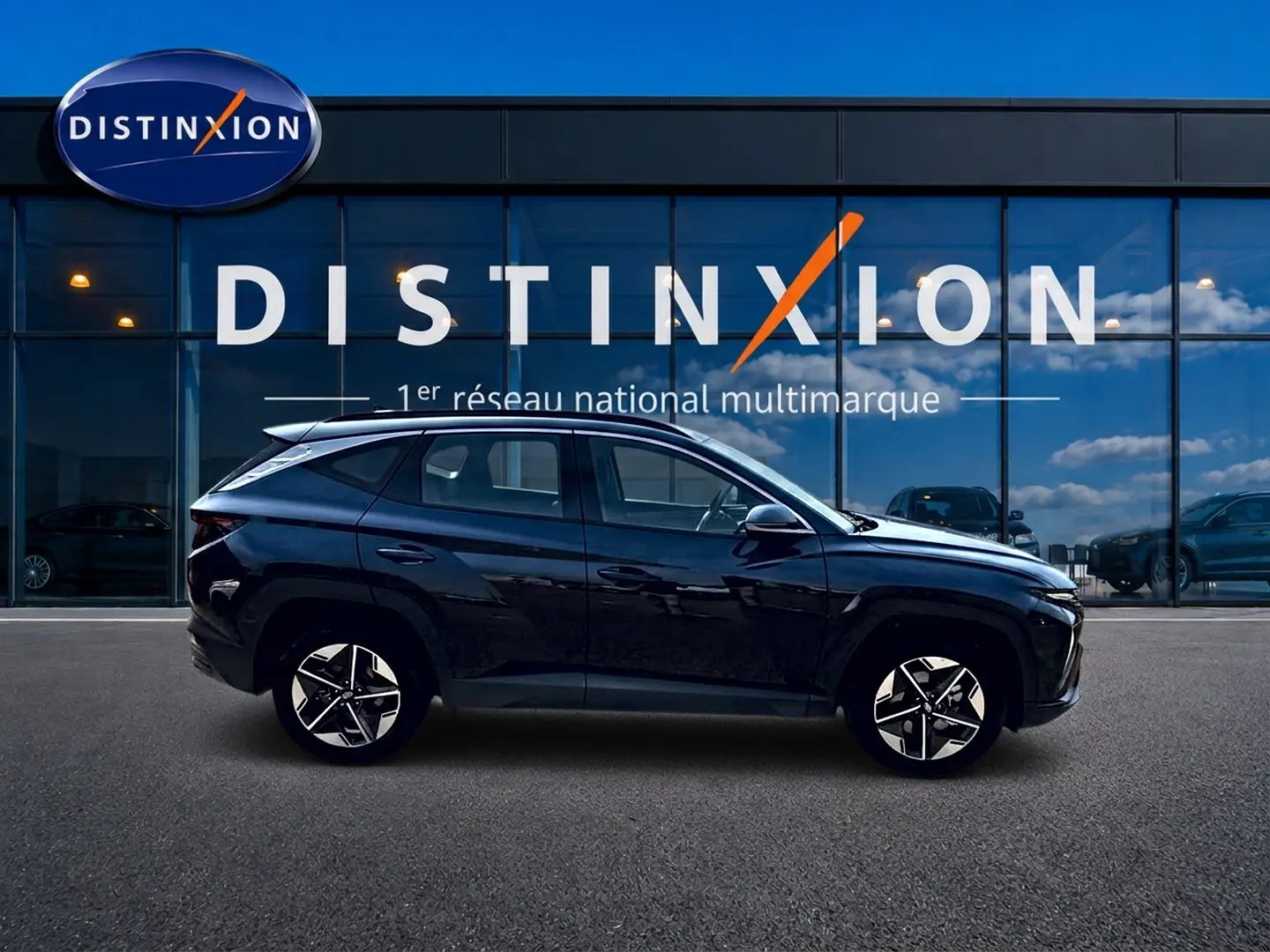 Profil droit du Hyundai Tucson noir 2026 hybride, avec jantes alu et lignes anguleuses modernes, devant une vitrine Distinxion.