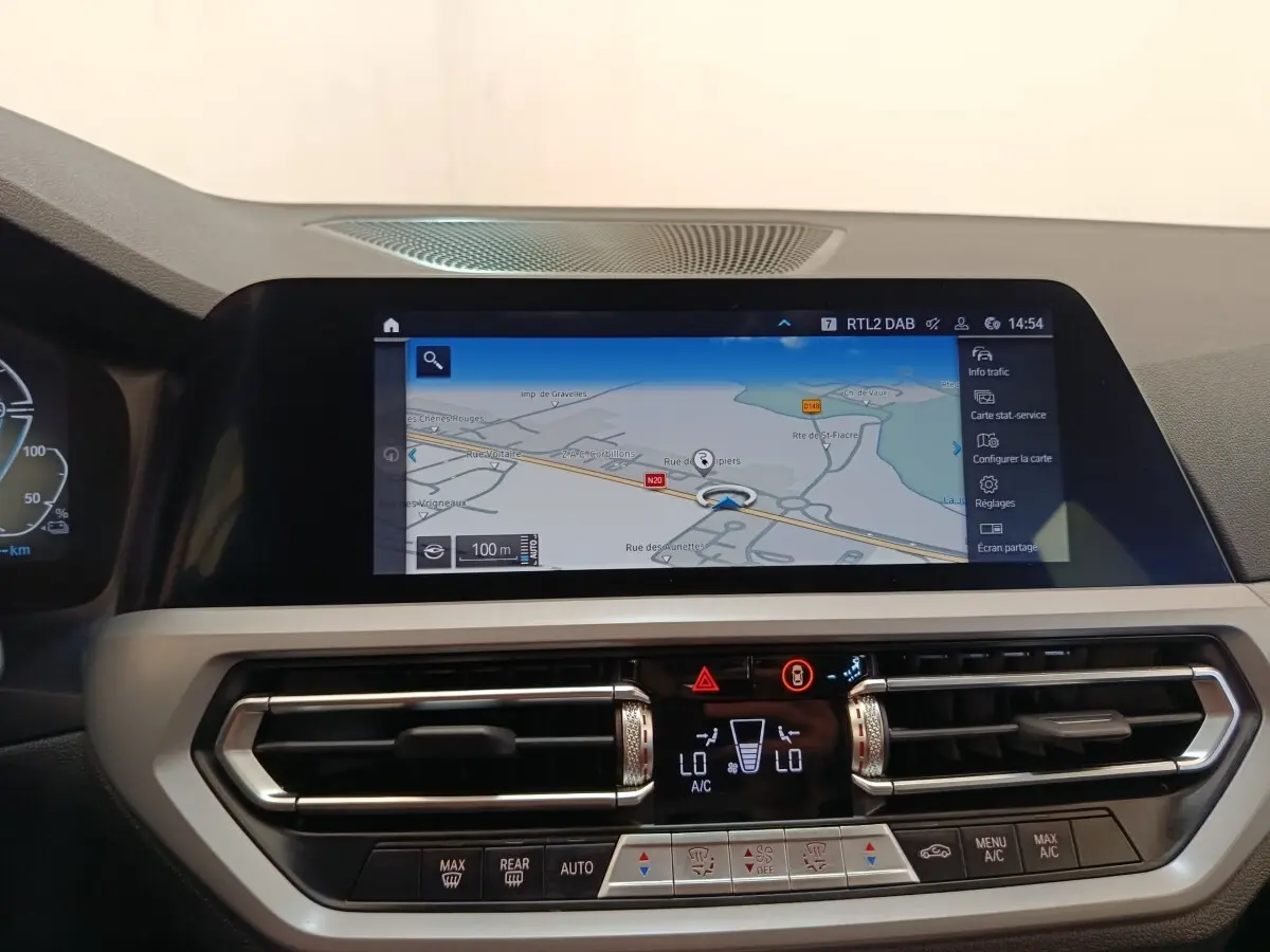 Vue intérieure du tableau de bord de la BMW Série 3 320e hybride avec écran tactile de navigation et commandes climatisation.