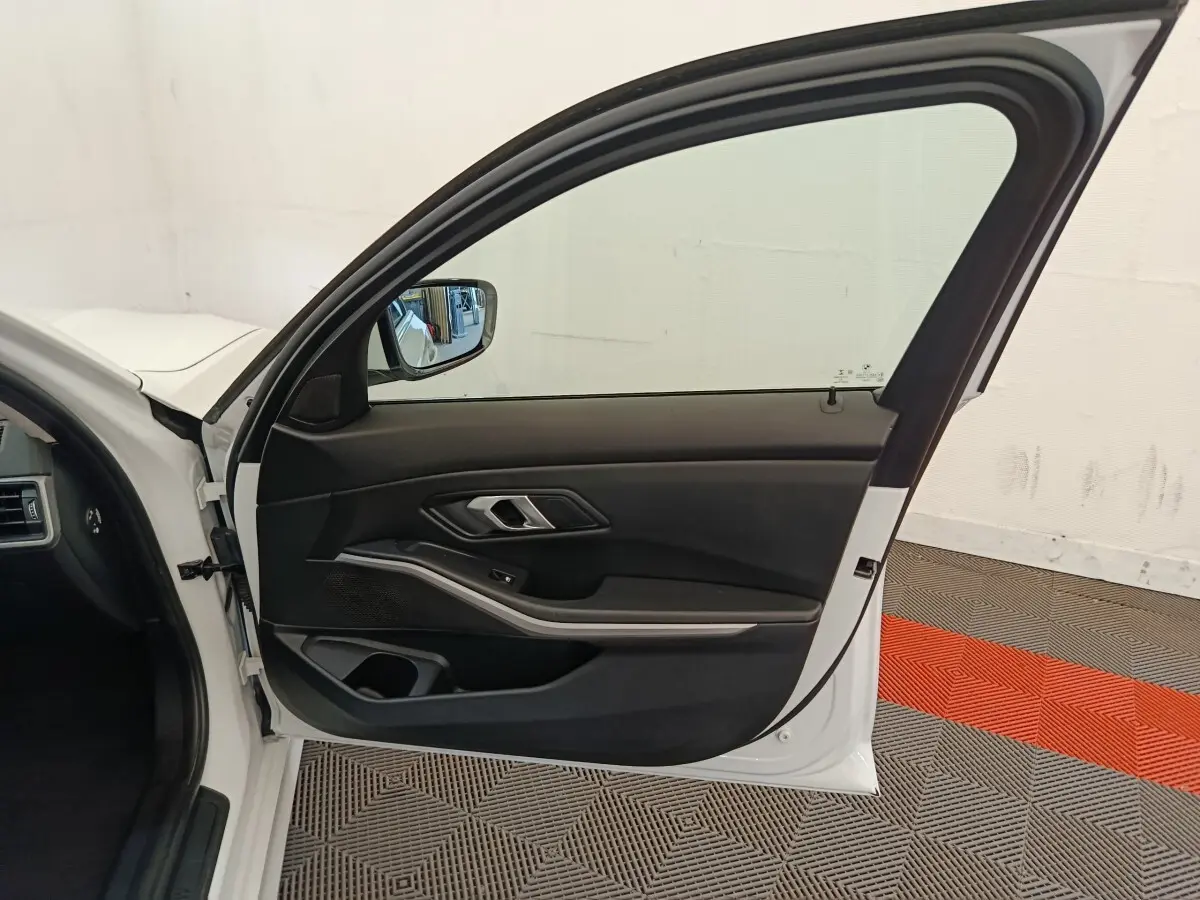 Vue intérieure de la porte avant gauche blanche d'une BMW Série 3 320e hybride, avec garniture noire et insert argenté.