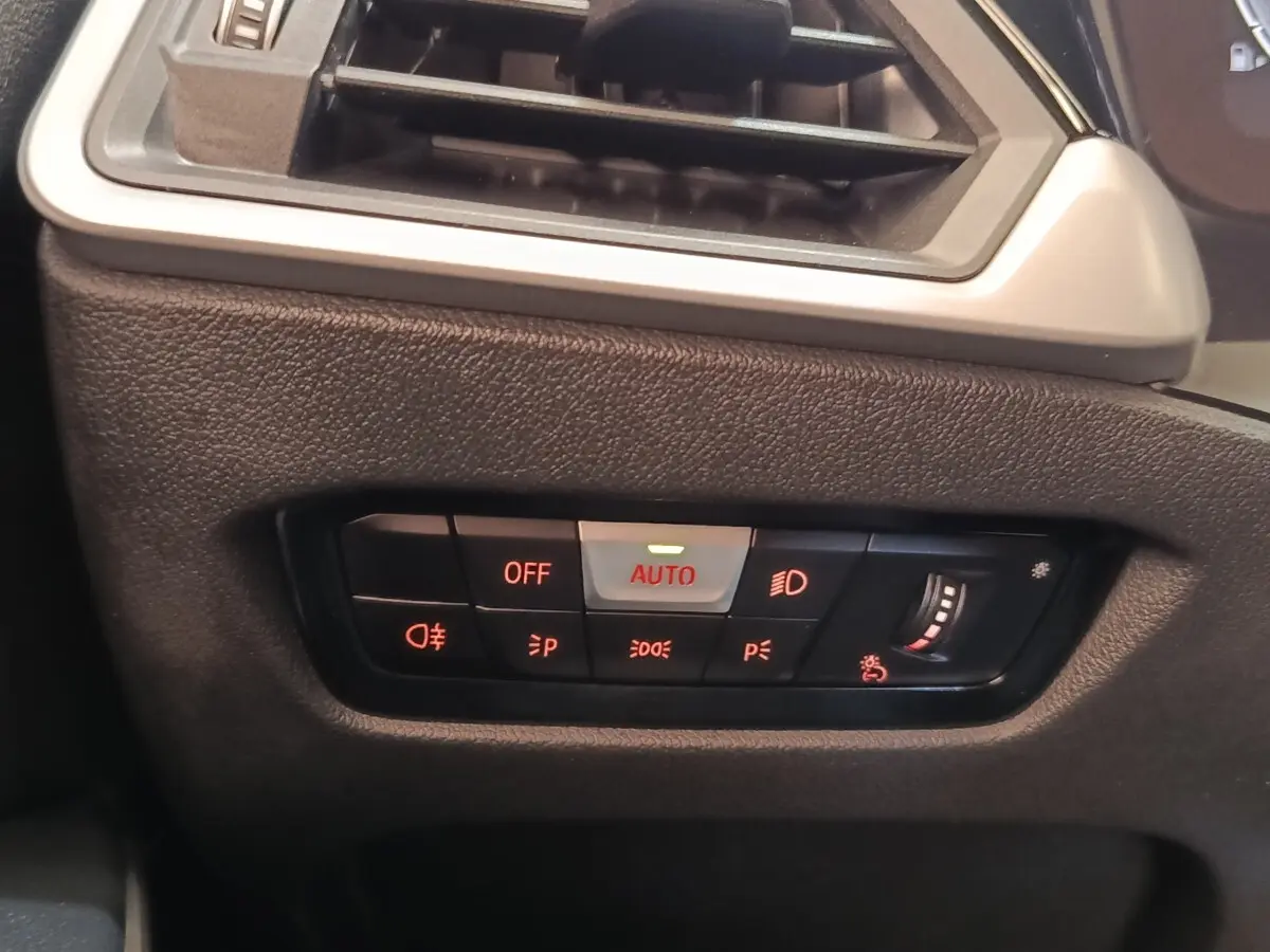 Détail du tableau de bord côté gauche de la BMW Série 3 320e blanche, avec commandes d’éclairage et ventilation.