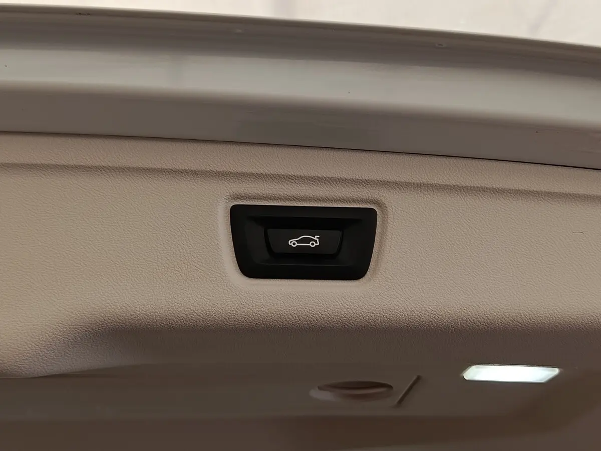 Bouton d'ouverture électrique du coffre sur la trappe intérieure d'une BMW Série 3 blanche hybride rechargeable.