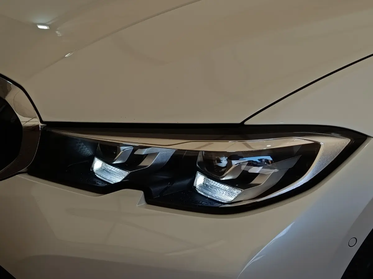 Gros plan sur le phare avant droit blanc d’une BMW Série 3 320e hybride rechargeable avec éclairage LED distinctif.