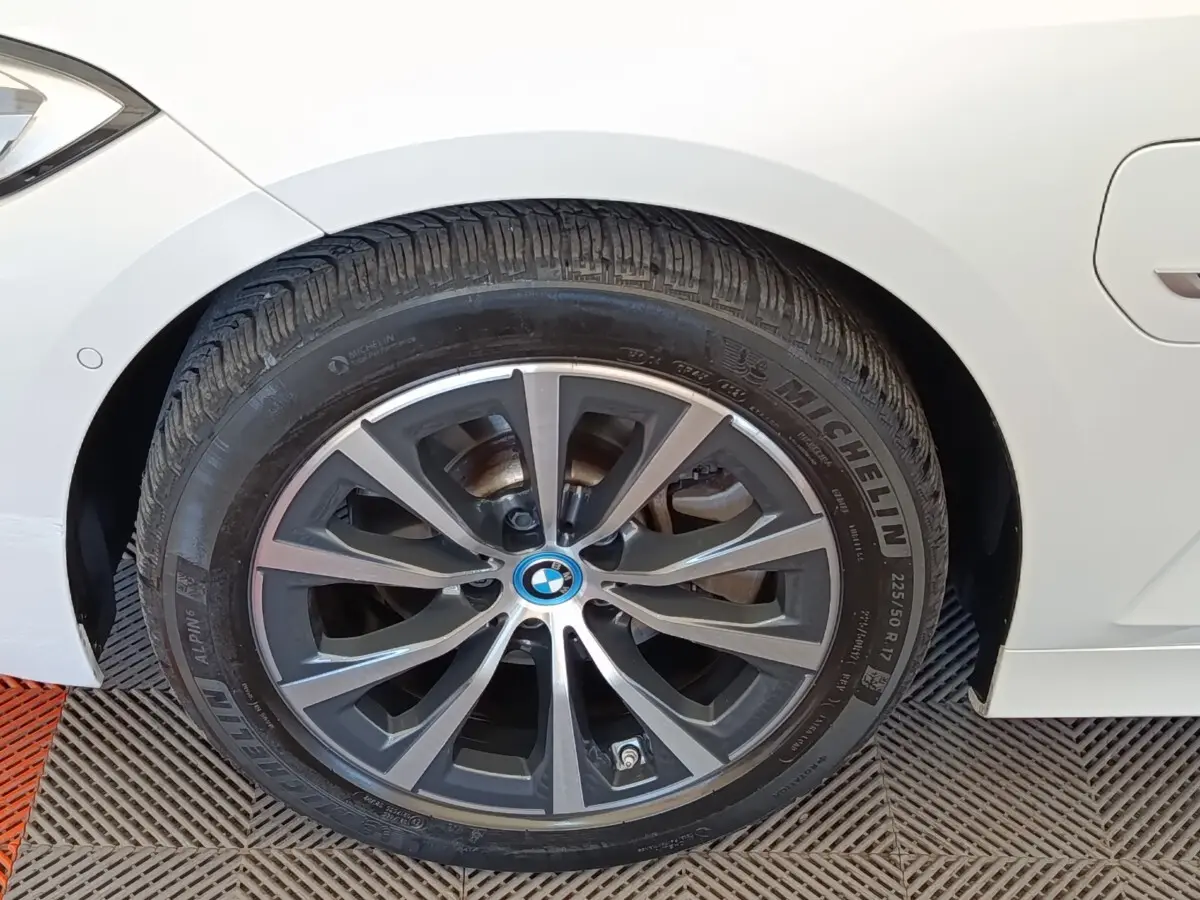 Gros plan sur la roue avant gauche d'une BMW Série 3 320e blanche avec jante alliage distinctive.