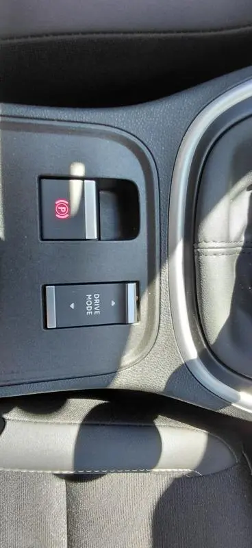 Gros plan sur les commandes de frein à main électronique et mode de conduite du Jeep Avenger 2025, intérieur noir.
