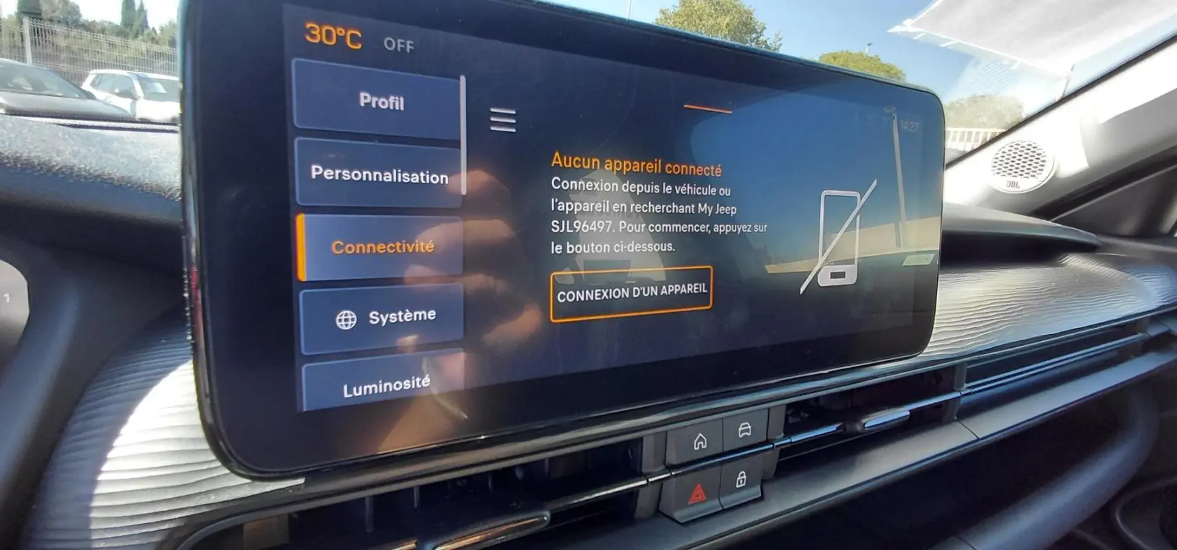 Écran tactile central du tableau de bord du Jeep Avenger blanc 2025, avec menu connectivité et haut-parleur JBL visible.