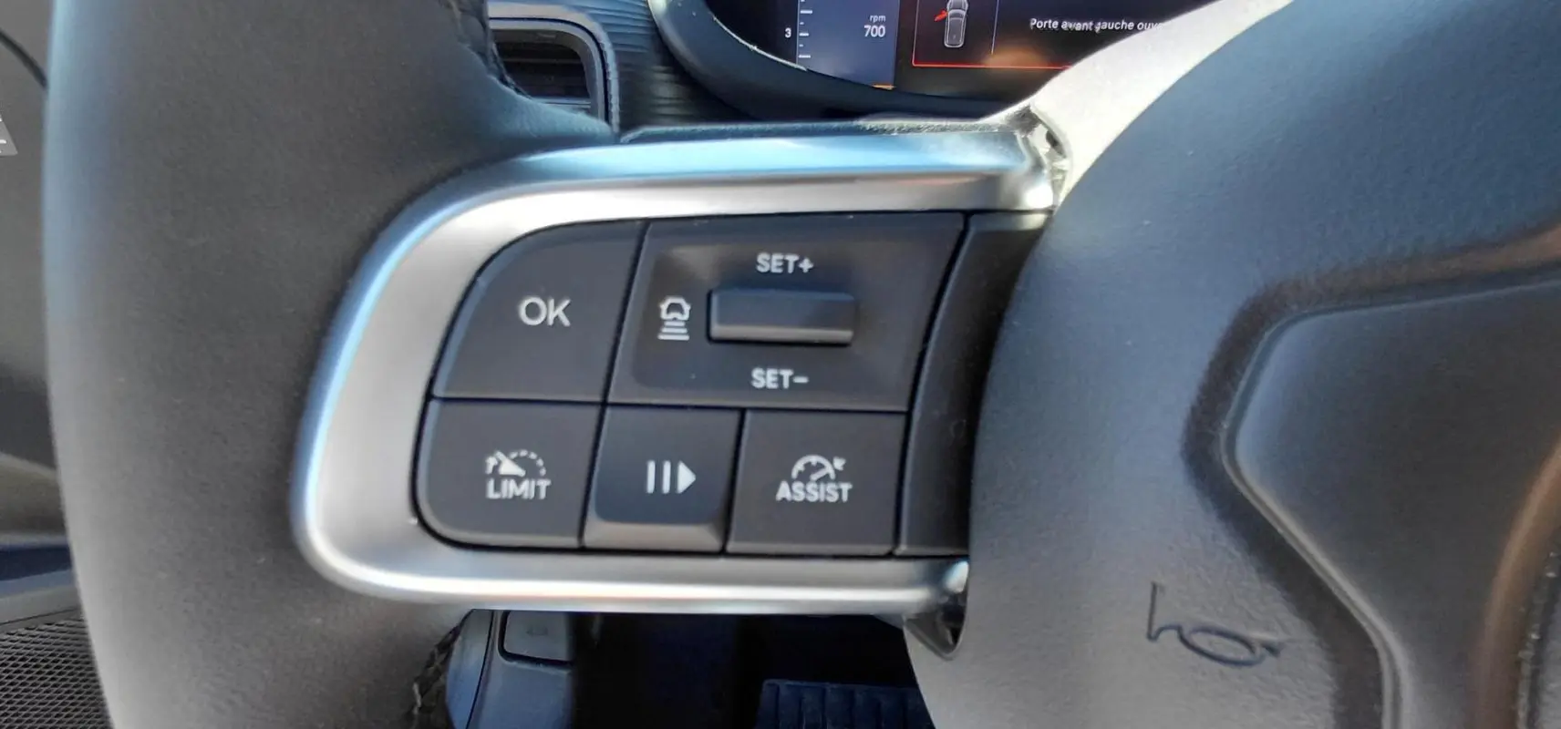 Gros plan sur les commandes au volant du Jeep Avenger blanc 2025, avec boutons de régulateur et assistance.