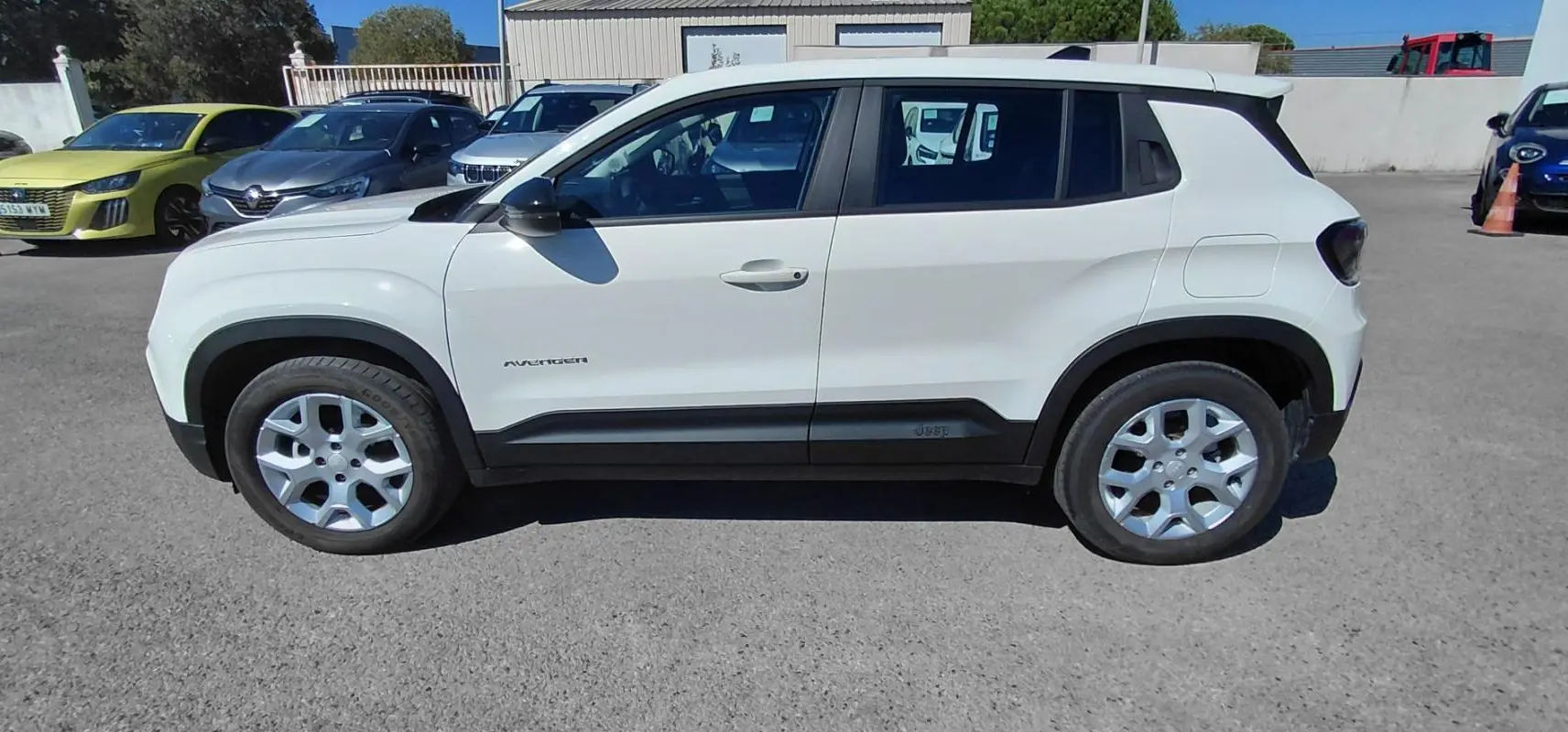 Jeep Avenger blanc vu de profil côté gauche, avec jantes alu et protections noires sur les bas de caisse.