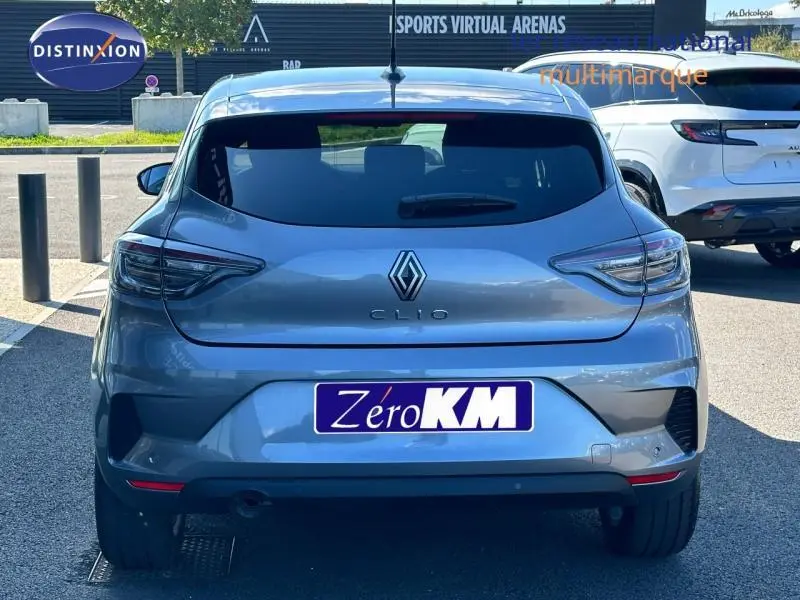 Vue arrière d'une Renault Clio gris Rafale 2025 avec feux LED et becquet arrière, stationnée en extérieur.