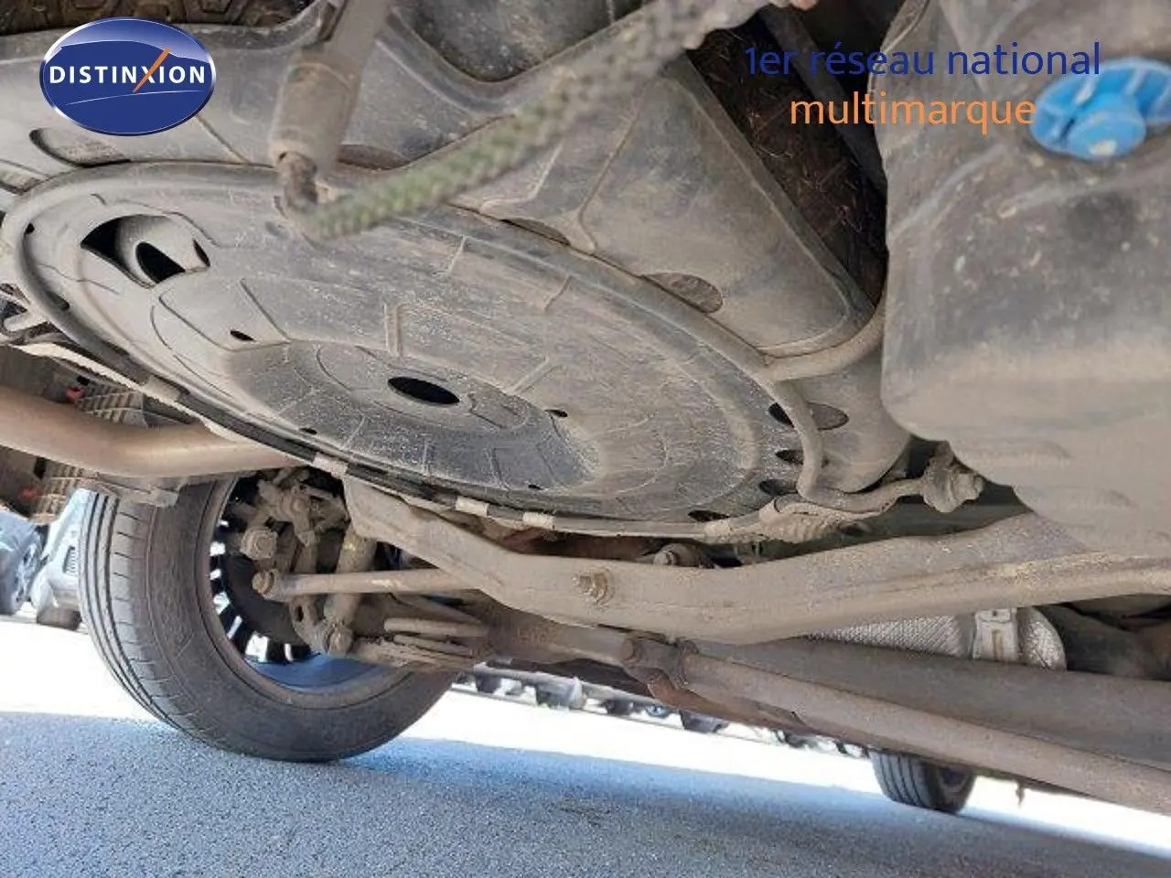 Vue en contre-plongée sous l'Opel Zafira noire métal, montrant le train arrière et la roue gauche.