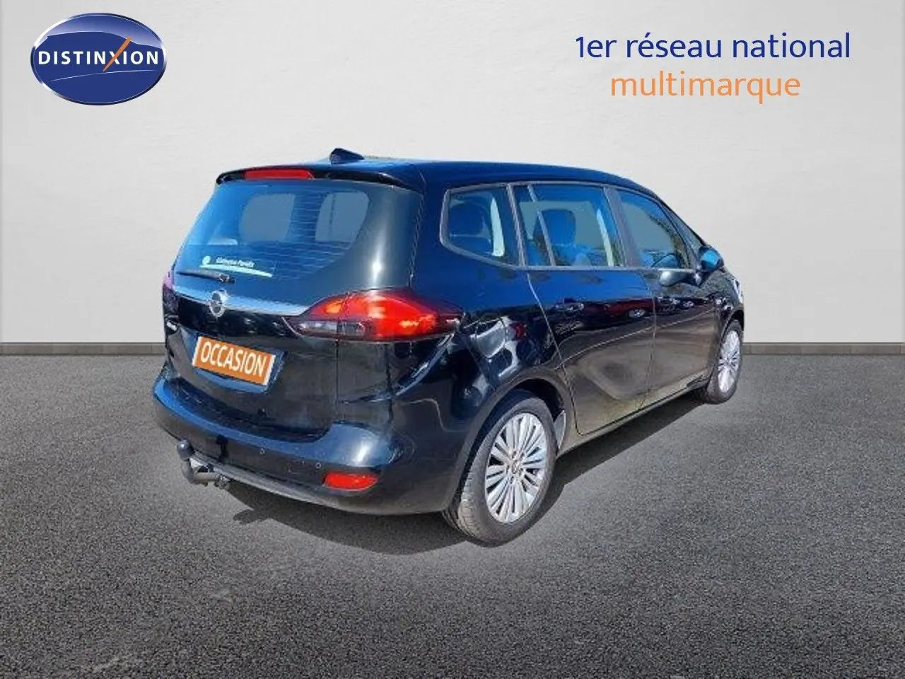 Opel Zafira noir métal en 3/4 arrière droit, montrant ses feux arrière et hayon avec attelage visible.