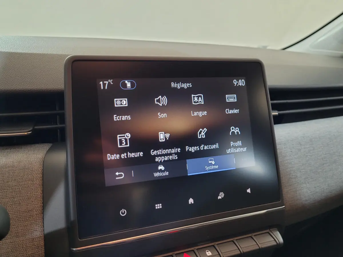 Écran tactile central affichant les réglages dans l'habitacle de la Renault Clio bleu, vue de face rapprochée.