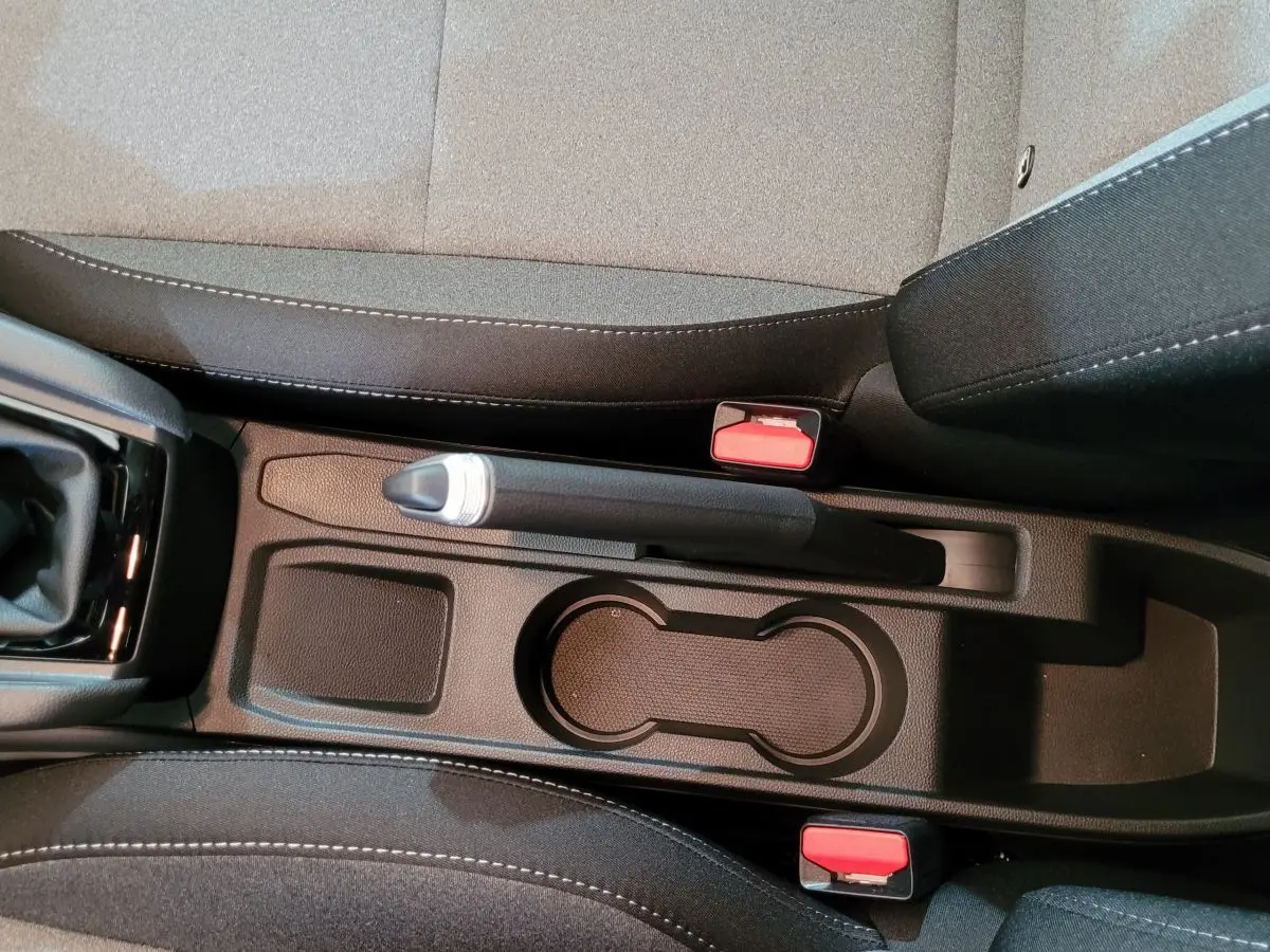 Vue plongeante sur la console centrale noire de la Renault Clio Evolution Blue dCi 100 avec frein à main manuel et porte-gobelets.