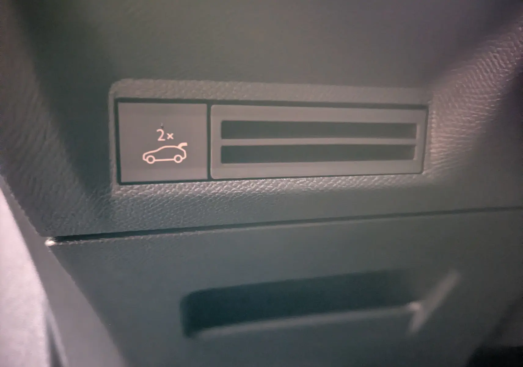 Détail intérieur du tableau de bord noir du Peugeot 3008 Hybrid, bouton d'ouverture du coffre avec symbole lumineux.