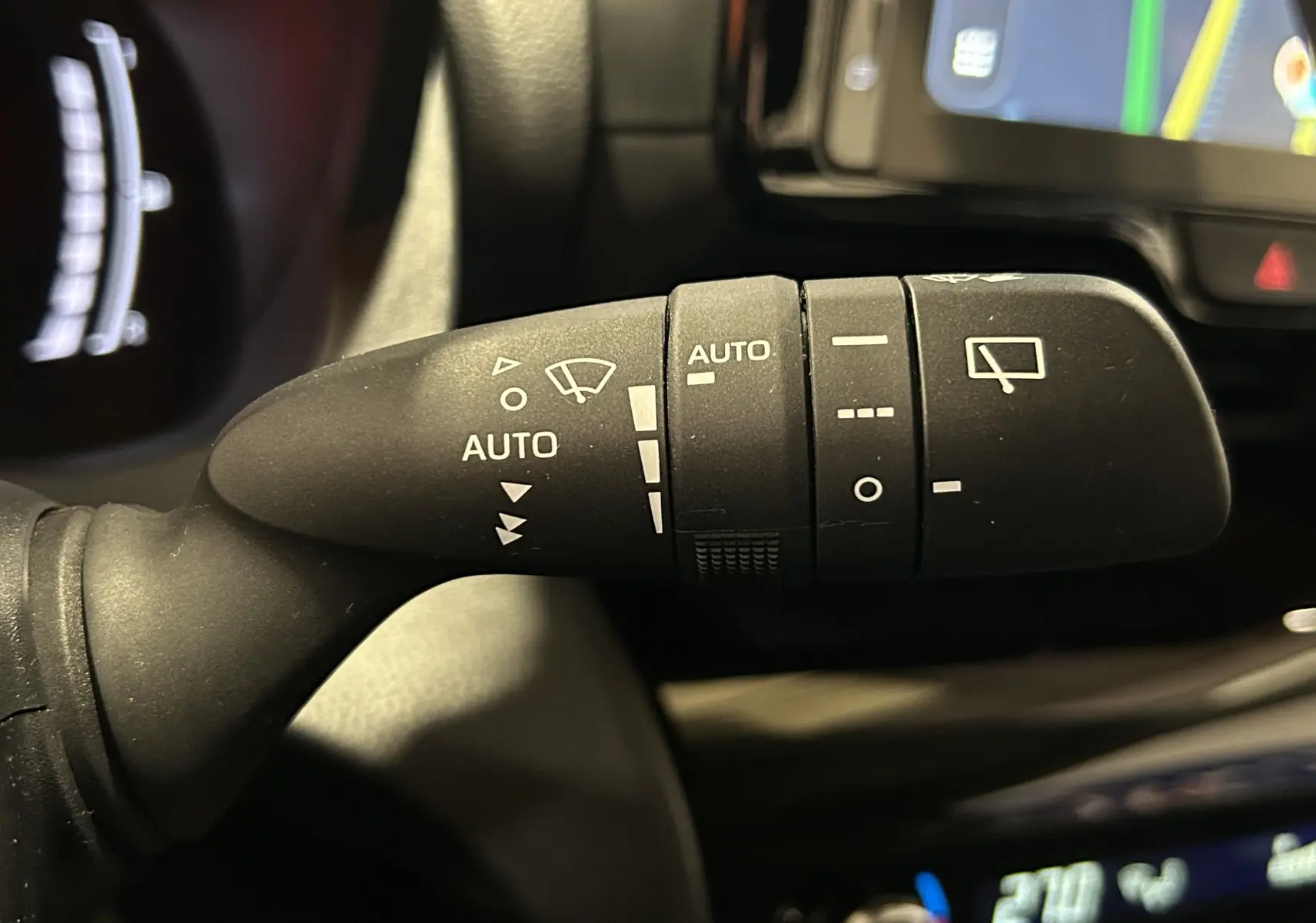 Gros plan sur la commande d’essuie-glace du Toyota Yaris Cross 116h Active gris minéral, intérieur avec écran tactile visible.