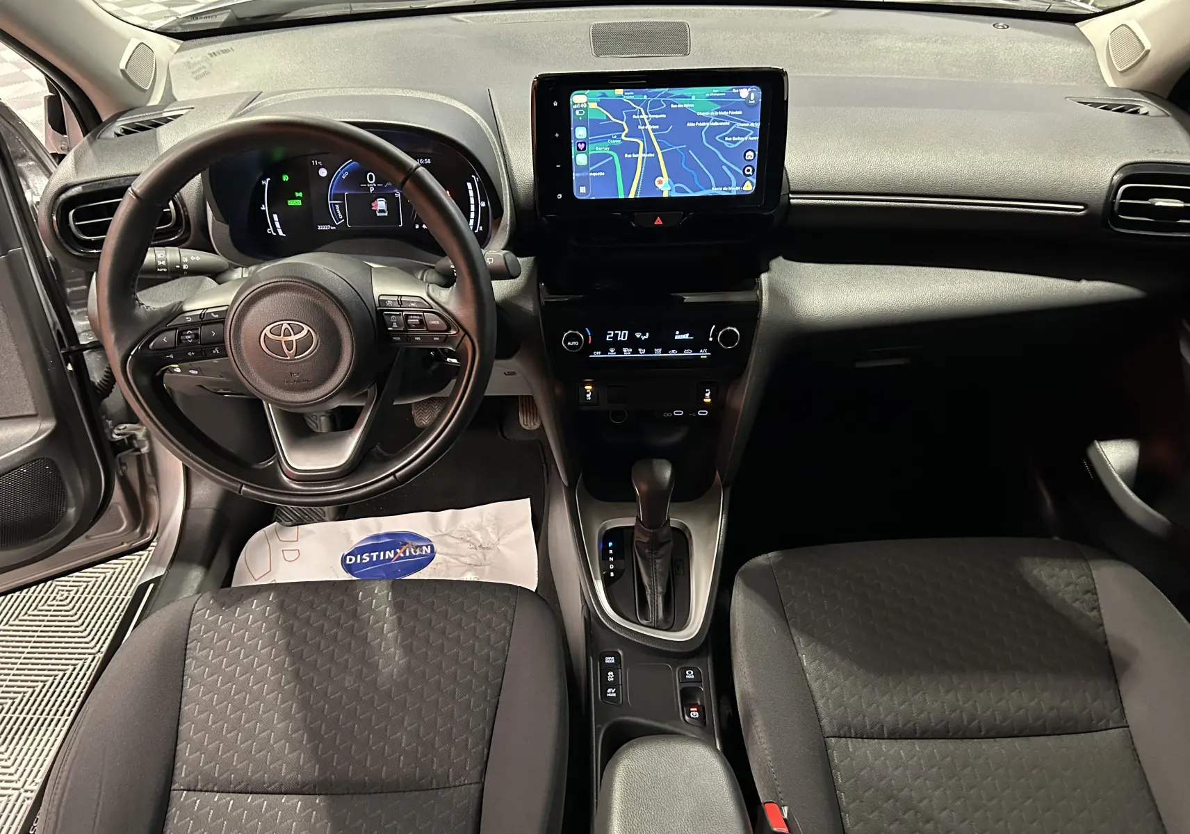 Vue intérieure frontale du tableau de bord et volant noir de la Toyota Yaris Cross 116h avec écran tactile et sièges tissu gris.