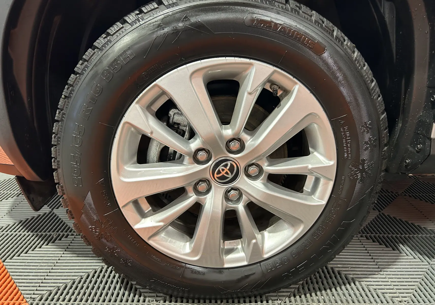 Gros plan sur la jante alliage argentée et pneu hiver d’une Toyota Yaris Cross gris minéral, roue avant droite.