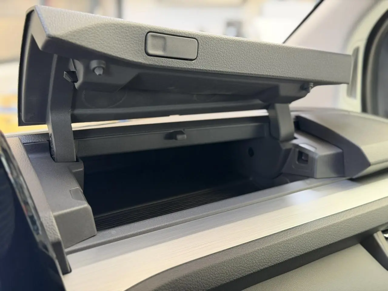 Gros plan intérieur sur la boîte à gants ouverte du Volkswagen Transporter T7 ProCab gris Stone, finition Business.