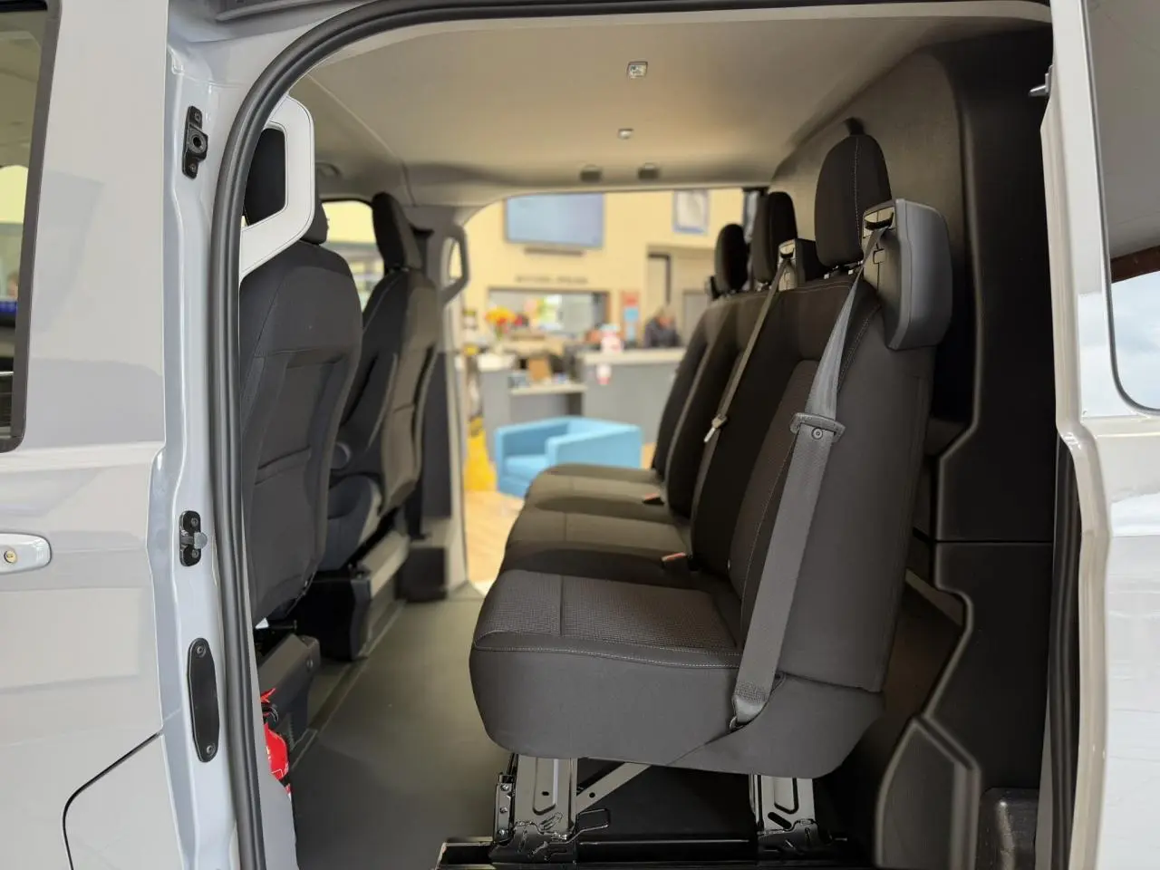 Vue intérieure côté gauche du Volkswagen Transporter T7 ProCab 2026, montrant les sièges noirs en tissu à rayures.