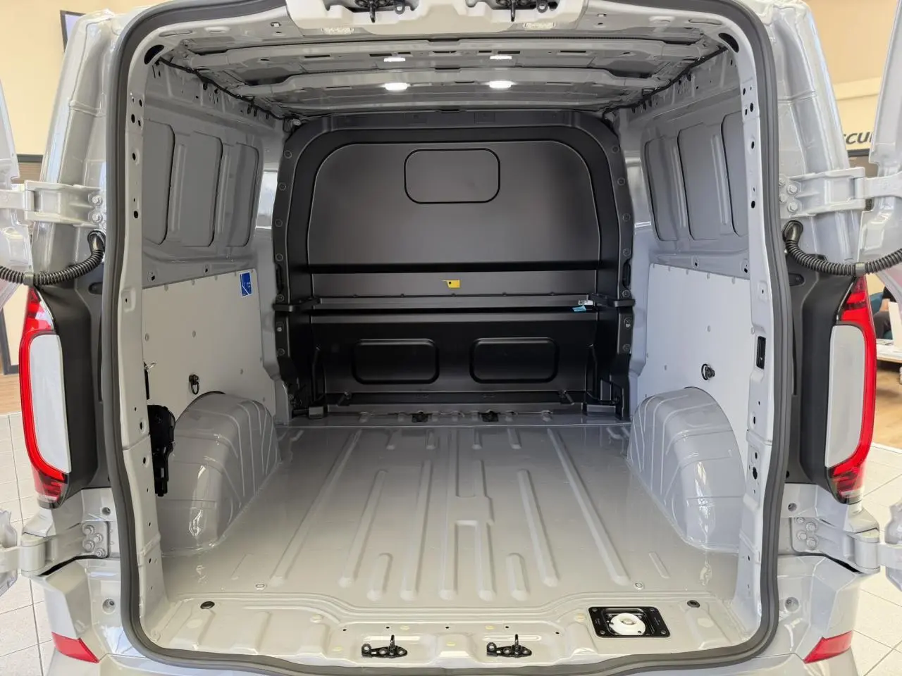 Vue arrière ouverte du Volkswagen Transporter T7 ProCab gris Stone, montrant l'espace de chargement vide et les portes battantes.