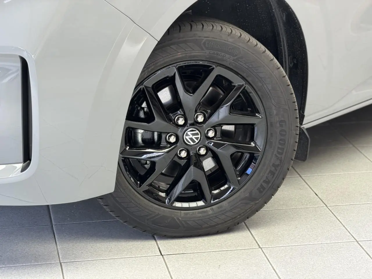 Gros plan sur la jante avant droite noire brillant Le Mans du Volkswagen Transporter T7 gris Stone.