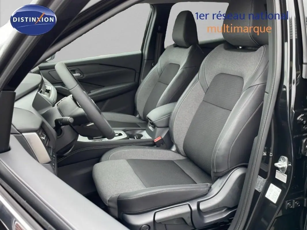 Vue intérieure côté conducteur du Nissan Qashqai noir 2025, sièges tissu et cuir gris, volant multifonctions visible.