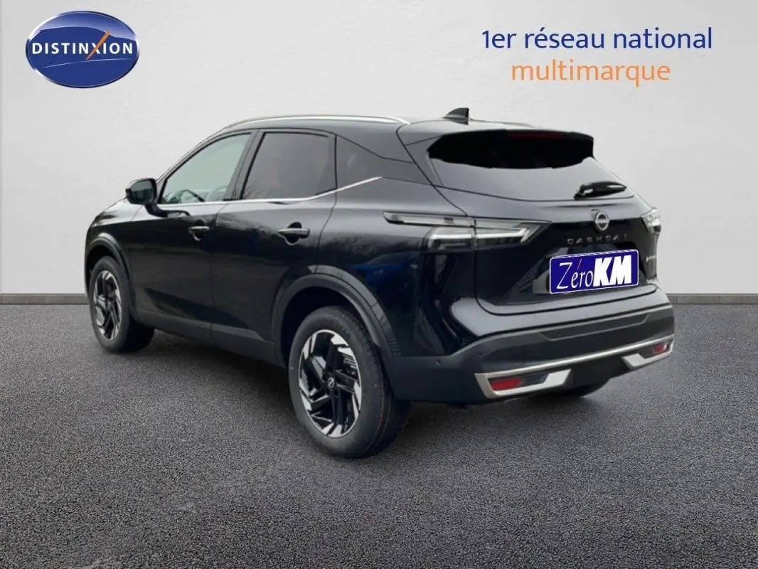 Vue 3/4 arrière droite du Nissan Qashqai noir 2025 avec jantes aluminium et barres de toit visibles.
