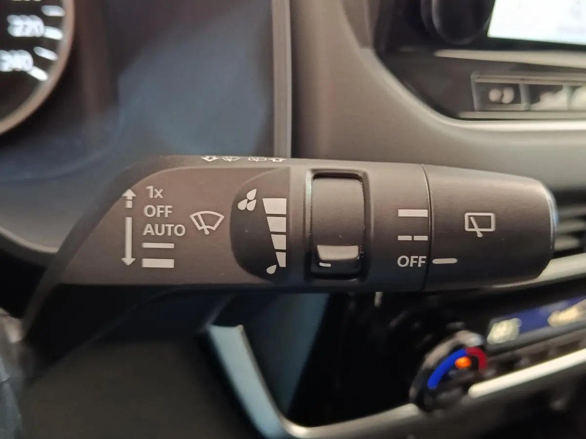 Gros plan sur la commande des essuie-glaces dans l’habitacle du Nissan Qashqai gris foncé, détails des symboles blancs visibles.