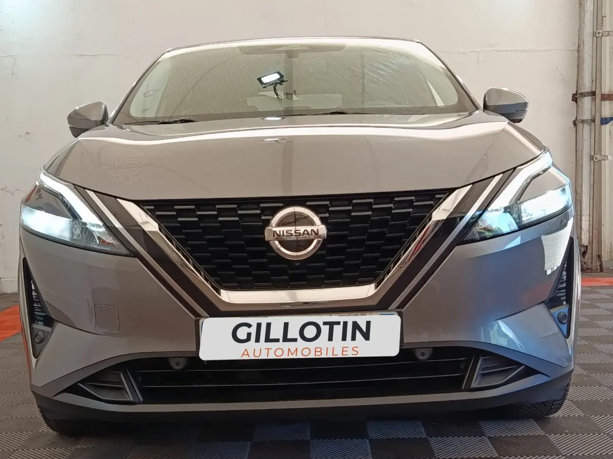 Vue frontale d'un Nissan Qashqai gris foncé avec phares LED allumés et calandre noire brillante.