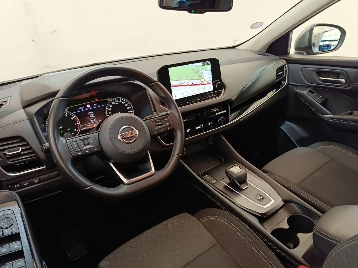 Vue intérieure côté conducteur du Nissan Qashqai 2022 avec tableau de bord noir et écran tactile central affichant la navigation.