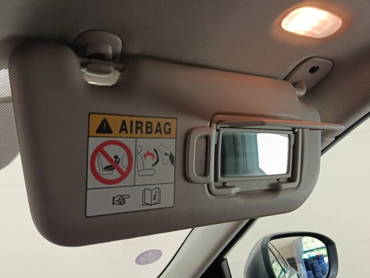 Détail du pare-soleil côté conducteur avec miroir intégré et étiquette d’avertissement airbag dans un Nissan Qashqai gris foncé.