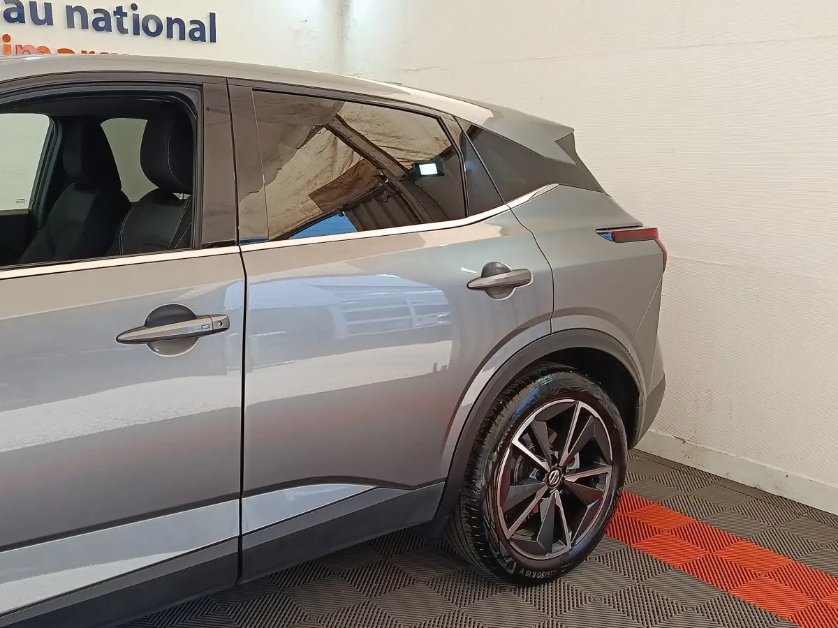 Vue latérale droite du Nissan Qashqai gris foncé 2022, mettant en valeur la roue arrière et les lignes modernes du véhicule.