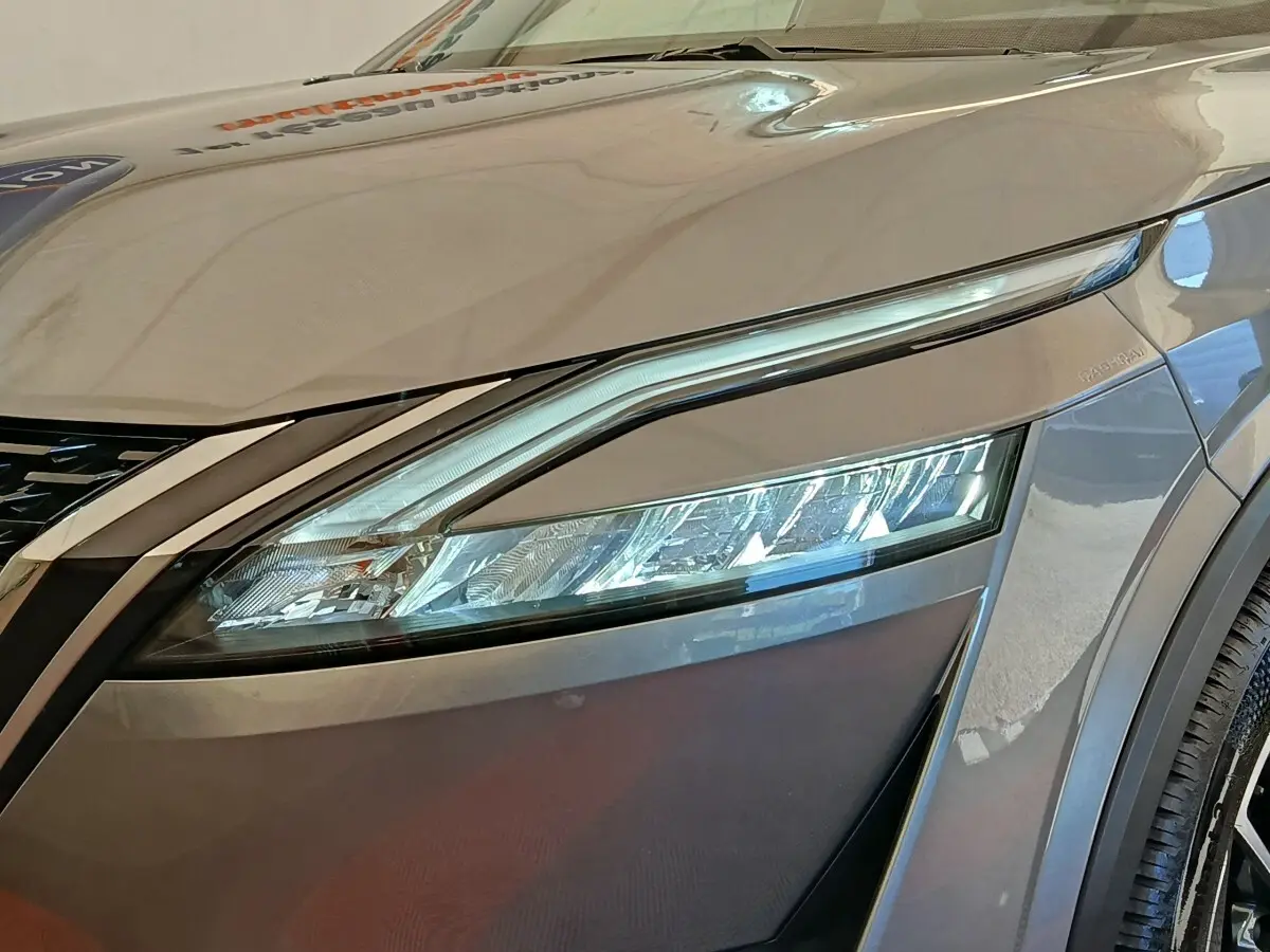 Gros plan sur le phare avant droit du Nissan Qashqai gris foncé, mettant en valeur son design LED moderne.