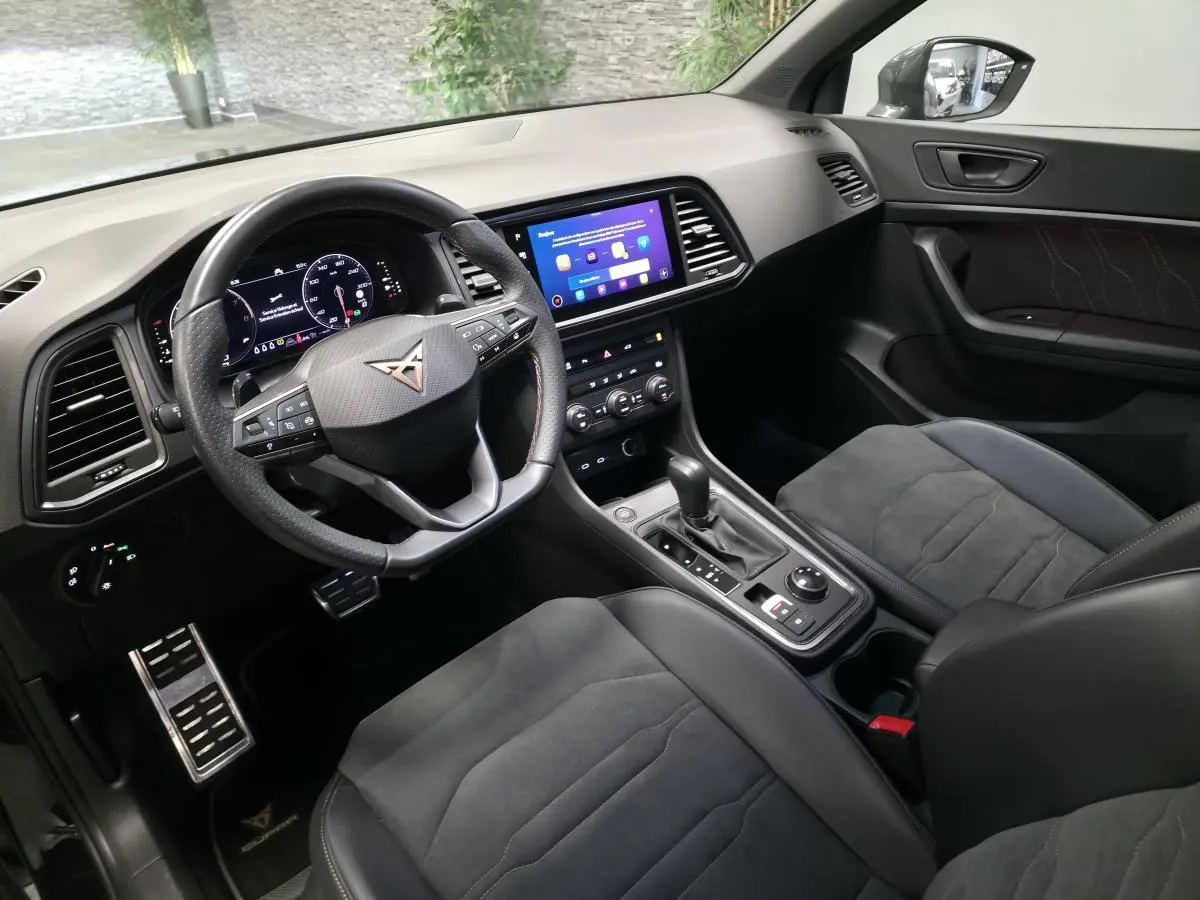 Intérieur noir du CUPRA Ateca 2024, vue côté conducteur, volant sport, écran tactile et sièges baquets en suédine.