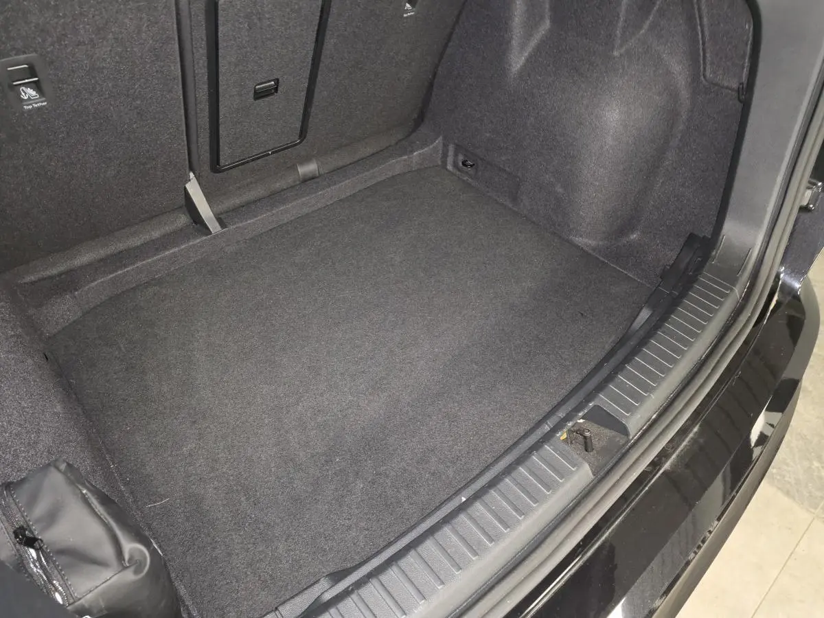 Coffre ouvert vu de dessus du CUPRA Ateca noir 2024, montrant le tapis de sol et l'espace de rangement intérieur.