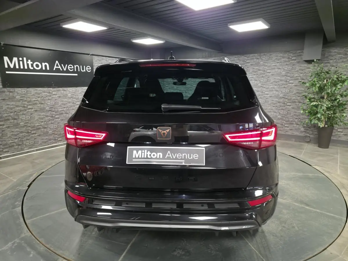 Vue arrière d'un CUPRA Ateca noir avec feux LED allumés et logo CUPRA cuivré sur hayon.