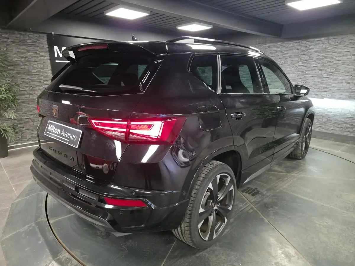 Vue 3/4 arrière droite d’un CUPRA Ateca noir brillant avec feux LED et jantes alliage 19 pouces dans un showroom.
