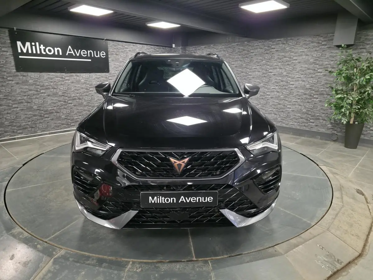 Vue avant d'un CUPRA Ateca noir avec calandre noire et logo cuivre, dans un showroom au sol gris.