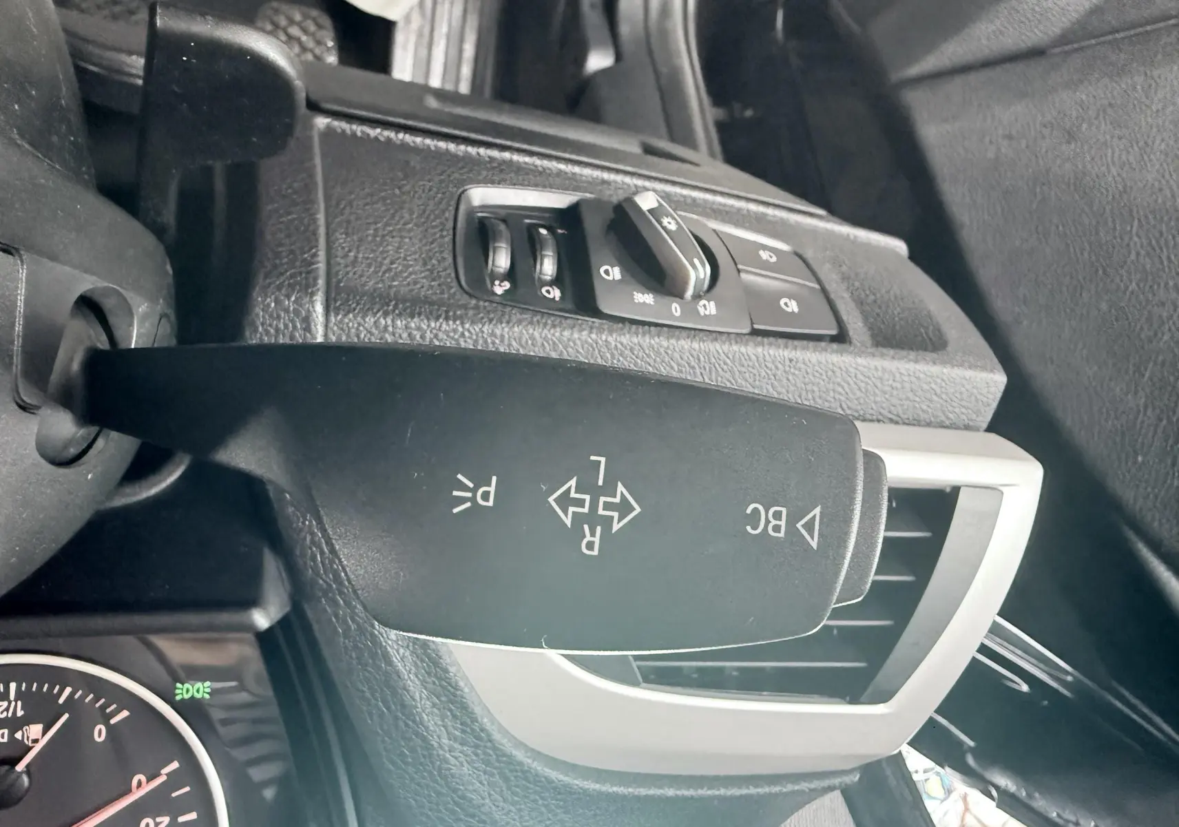 Gros plan sur la commande de clignotants à gauche du volant dans l’habitacle noir d’une BMW Série 1 2016.