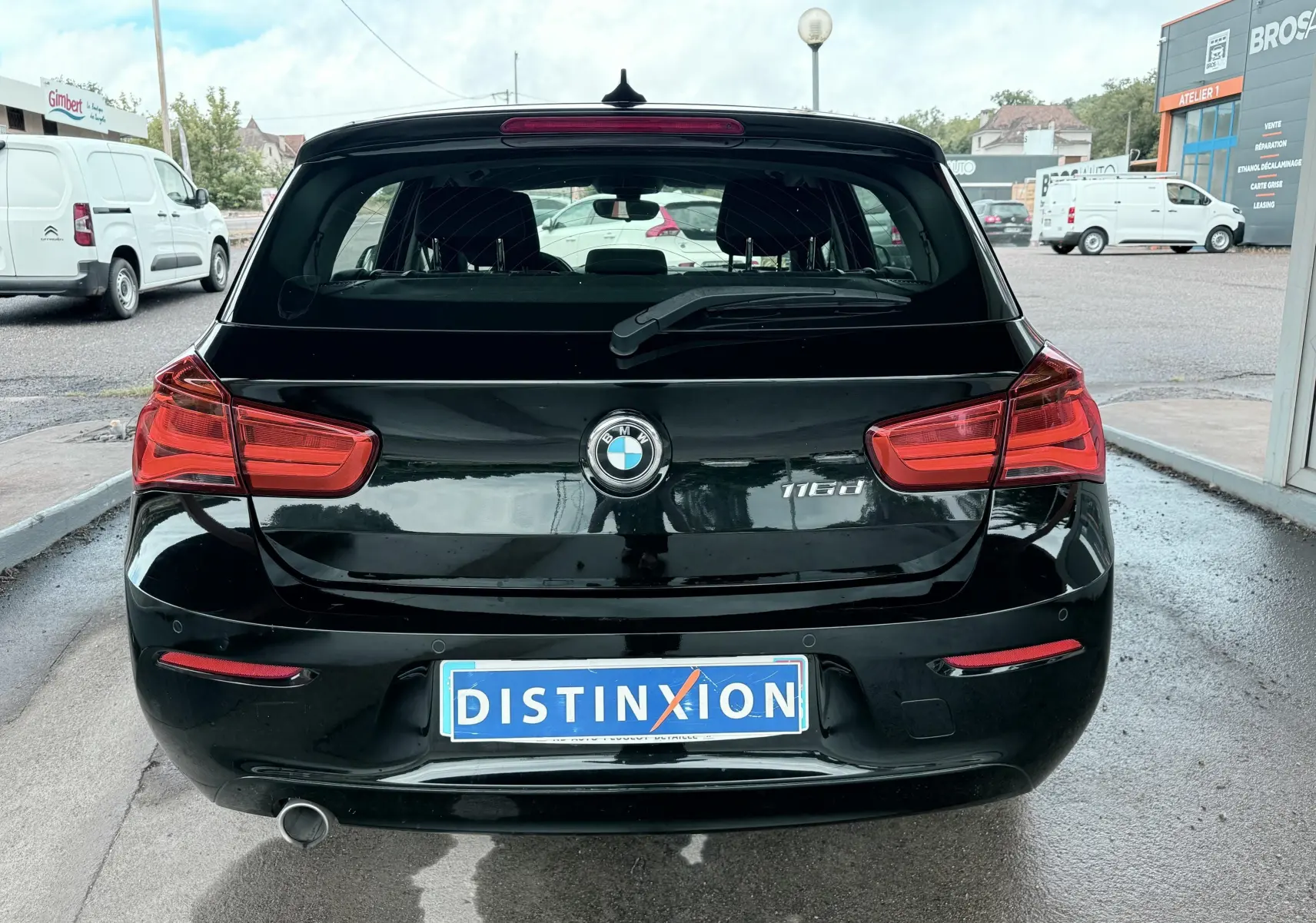 Vue arrière d'une BMW Série 1 noire 116d avec feux rouges et plaque d'immatriculation Distinxion.