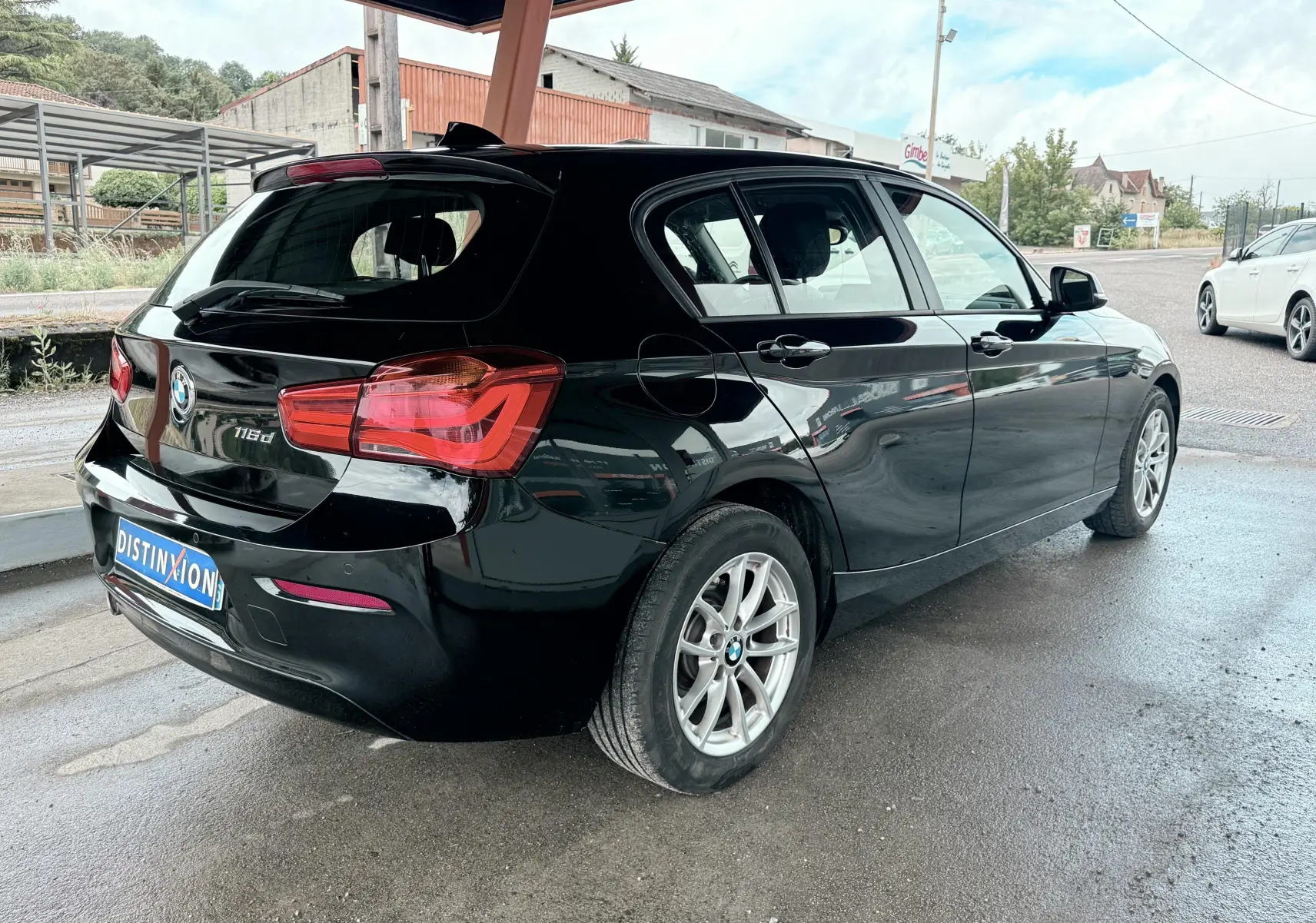 BMW Série 1 noire vue en 3/4 arrière droit, mettant en valeur ses feux arrière et ses jantes argentées.