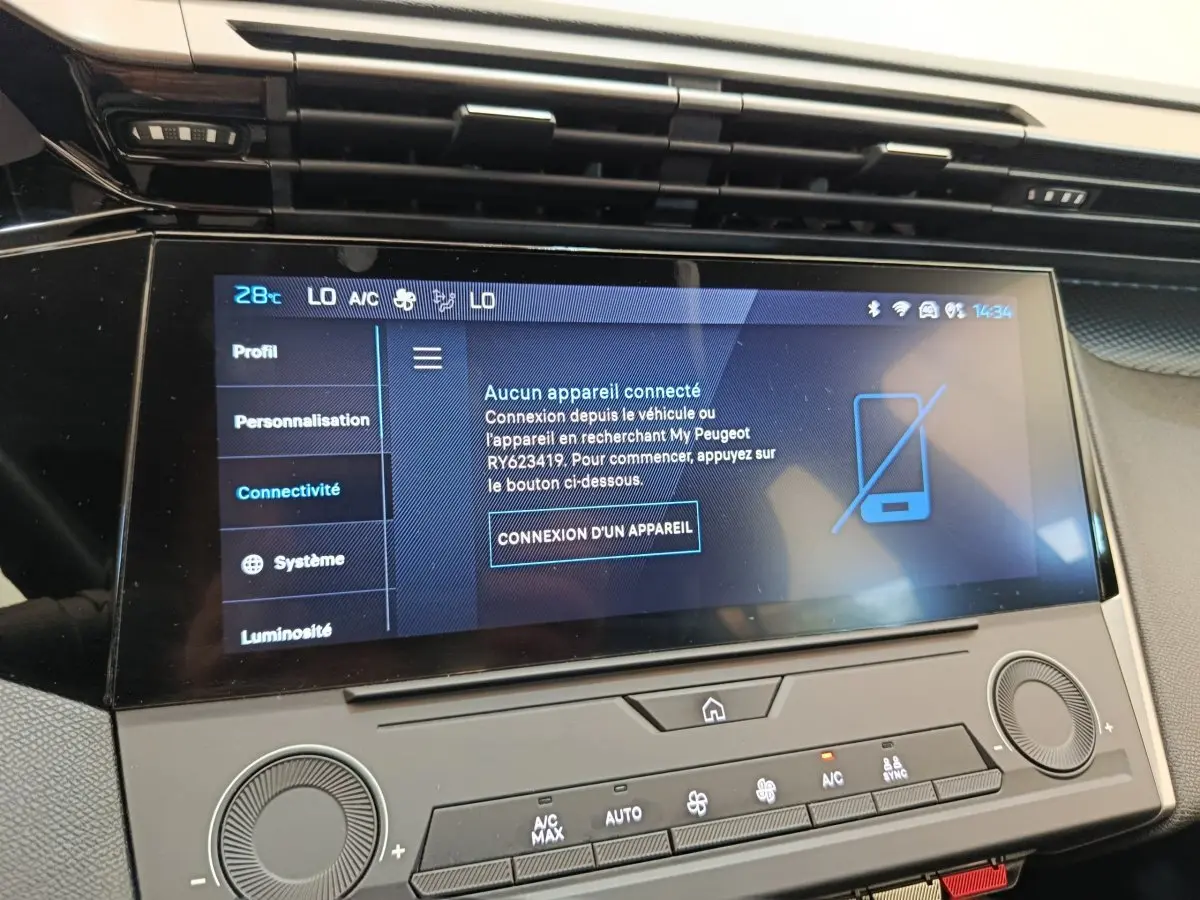 Écran tactile central affichant le menu connectivité dans l’habitacle d’une Peugeot 308 blanche, vue de face rapprochée.