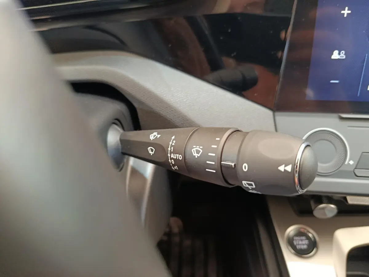 Gros plan sur la commande des essuie-glaces à gauche du volant dans l’habitacle d’une Peugeot 308 blanche 2024.