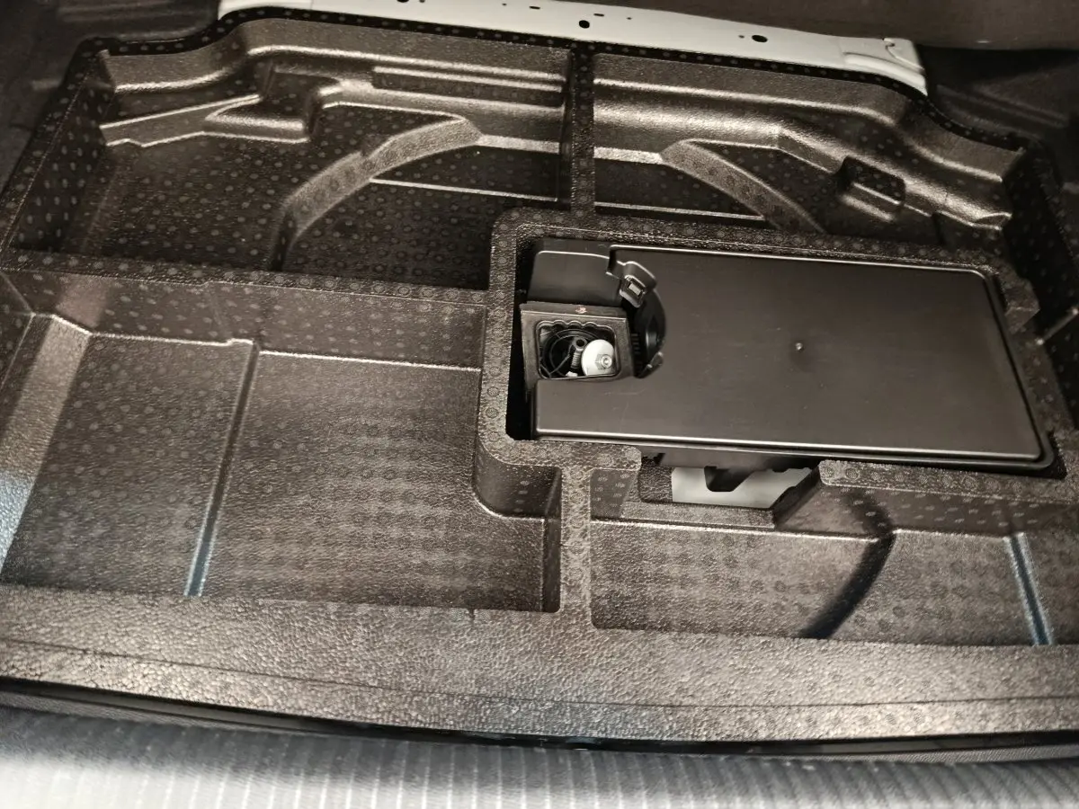 Vue rapprochée du compartiment de rangement sous le plancher du coffre de la Peugeot 308 blanche 2024.