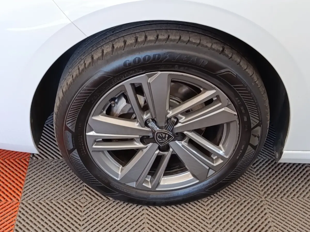Gros plan sur la roue avant gauche d'une Peugeot 308 blanche avec jante alliage et pneu Goodyear.