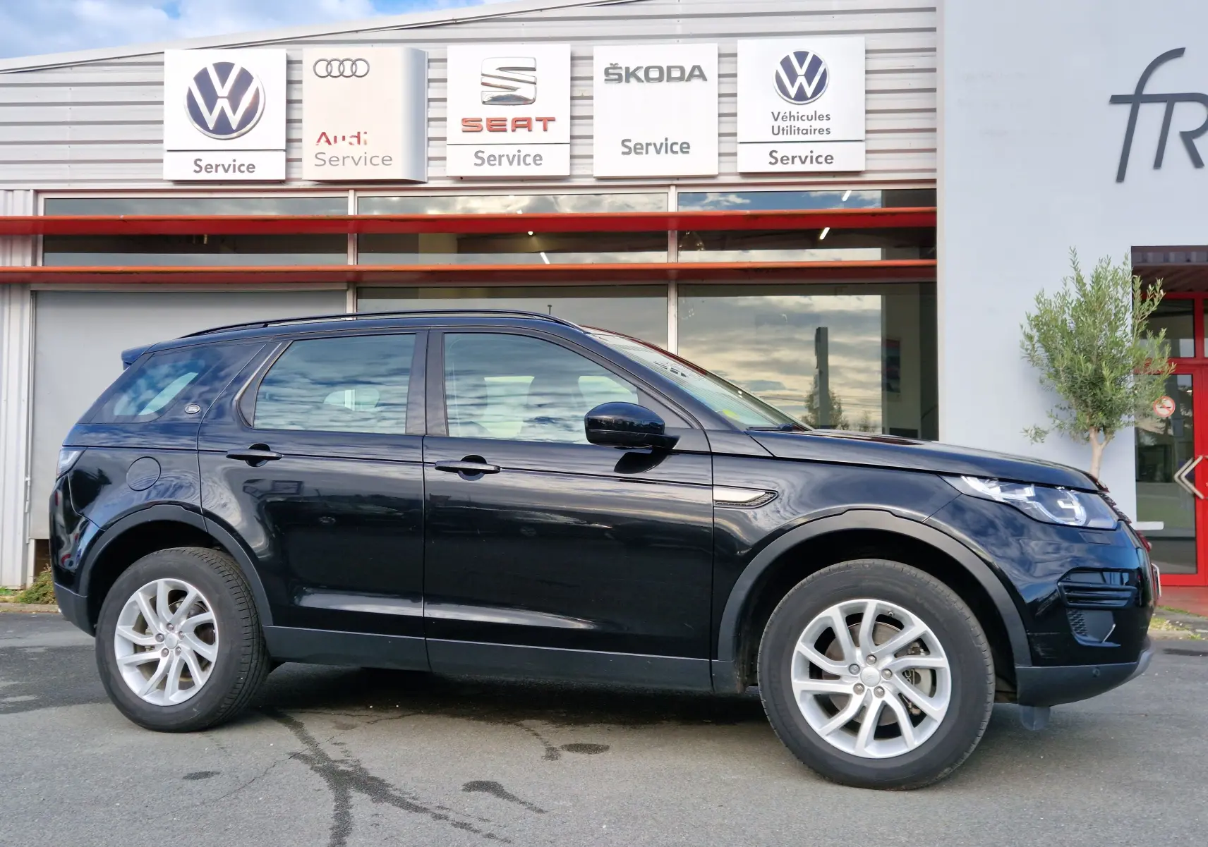 Vue 3/4 avant d'un Land Rover Discovery Sport Mark II noir de 2017 avec calandre distinctive et jantes argentées.