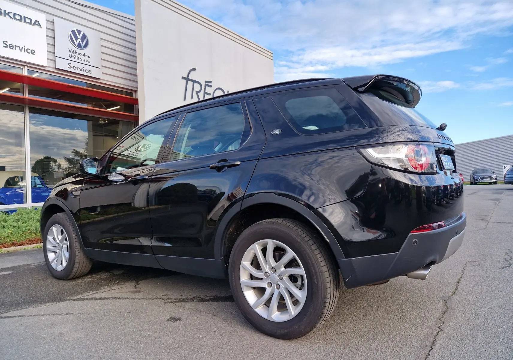 Gros plan sur le phare avant gauche d'un Land Rover Discovery Sport noir de 2017, mettant en valeur son design moderne.